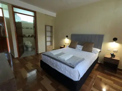 a bedroom with a large bed and a bathroom at Apu Garden Lodge in Urubamba