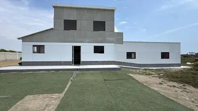 a white building with black windows on a field at Amplia casa petfriendly con parrilla cerca a Asia in Salitre