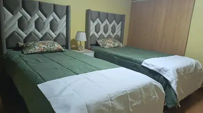two beds in a bedroom with green and white at Boulevard home hostel - Lima Airport in Lima