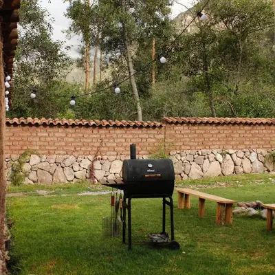 a grill in a yard next to a brick wall at Cancha Wasi A modern, cozy and fully equipped house in Urubamba