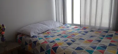 a quilt on a bed in a bedroom with a window at Condominio Vive Paracas in Puerto Nuevo