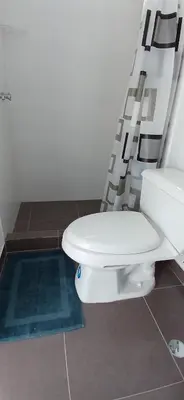 a white toilet in a bathroom with a ladder at Condominio Vive Paracas in Puerto Nuevo