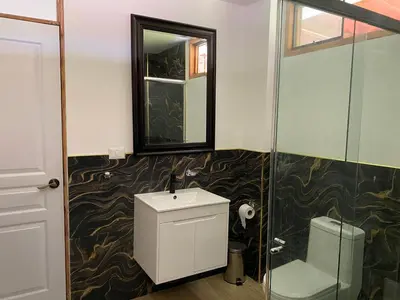 a bathroom with a toilet and a glass shower at La Casona - Hospedaje Campestre in El Carmen