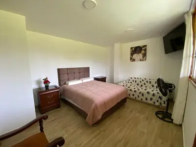 a bedroom with a bed and a dresser in it at La Casona - Hospedaje Campestre in El Carmen