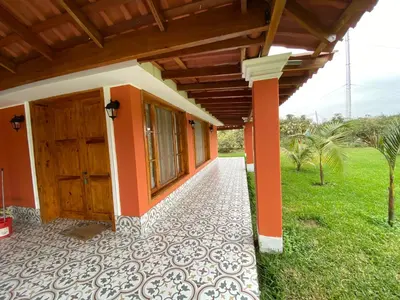a house with a wooden door and a grass field at La Casona - Hospedaje Campestre in El Carmen