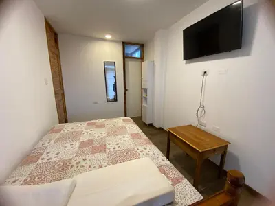 a bedroom with a bed and a tv on the wall at La Casona - Hospedaje Campestre in El Carmen