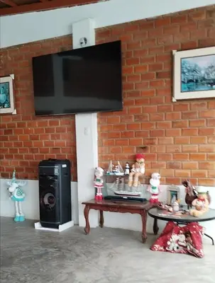 a television hanging on a brick wall with a coffee table at Finca Lucía Kemper in San Vicente de Cañete