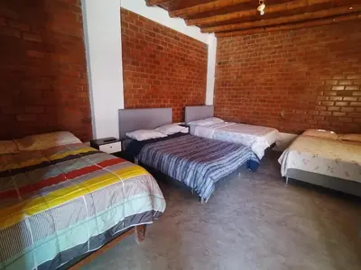 two beds in a room with a brick wall at Finca Lucía Kemper in San Vicente de Cañete