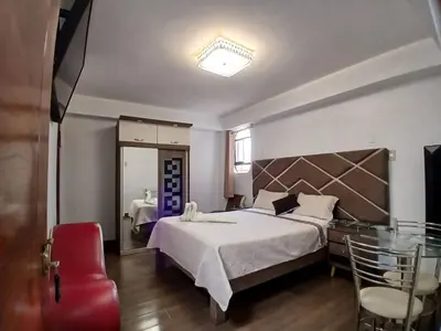 a bedroom with a large bed and a red chair at Princess Hotel in Supe
