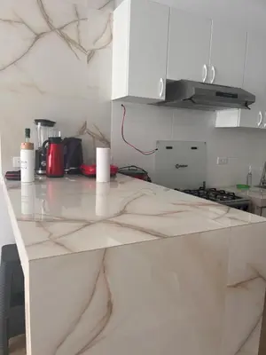 a white kitchen with a marble counter top at Departamento 101 in Punta Negra