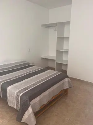 a bed in a white room with white shelves at Departamento 101 in Punta Negra