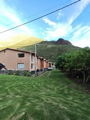 a house with a green yard with a mountain in the background at Condomino Villa Andina in Urubamba