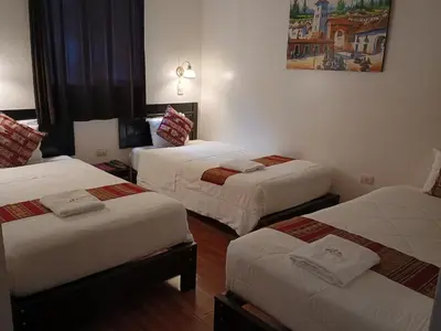a hotel room with three beds in a room at Hostal Killari Machupicchu in Machu Picchu