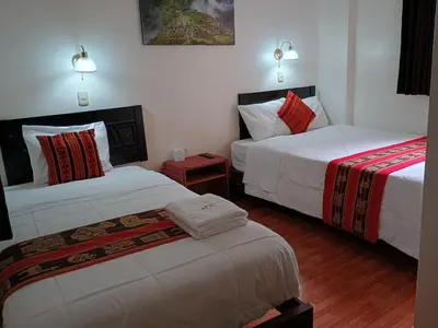 a hotel room with two beds and two tables at Hostal Killari Machupicchu in Machu Picchu