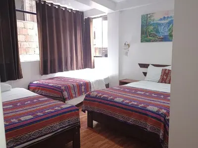 a room with two beds and two windows at Hostal Killari Machupicchu in Machu Picchu