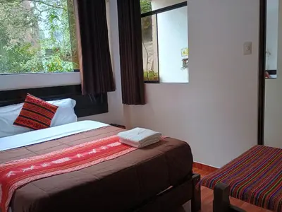 a small bedroom with a bed and a window at Hostal Killari Machupicchu in Machu Picchu