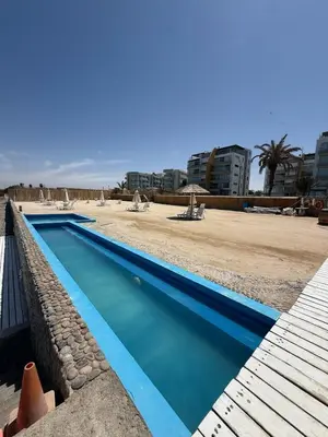 a swimming pool next to a beach with buildings at Oceanfront apartment con opcion de Velero in Paracas