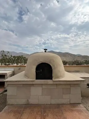 a stone oven on a roof with mountains in the background at Casa de campo Rosenthal - Cieneguilla in Panquilma