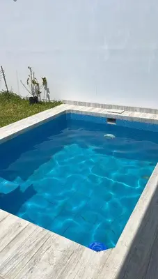 a large blue swimming pool with a wooden deck at CASA CERCA a PLAYA NAPLO CON PISCINA in Pucusana