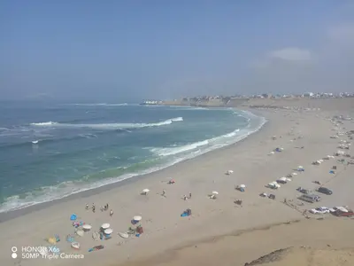 a beach with people and umbrellas and the ocean at Mini Depa km 43 Punta hermosa in Punta Hermosa