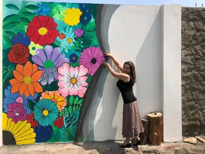 a woman standing in front of a flower mural at Las Delicias in Huacho
