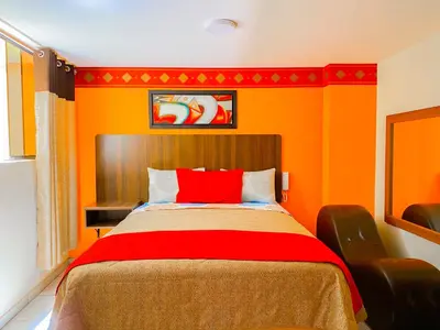 a bedroom with orange walls and a bed with a red pillow at Hostal Mayra Breña in Lima