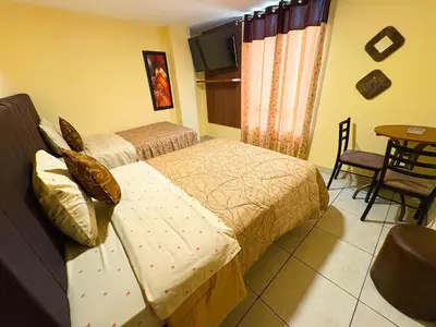 a bedroom with two beds and a table and chairs at Hostal Mayra Breña in Lima