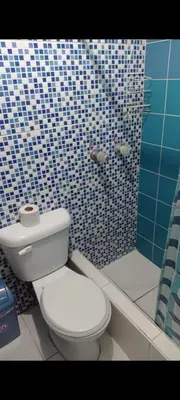 a bathroom with a white toilet and a blue tiled shower at Hospedaje Puerto Escondido in Pucusana