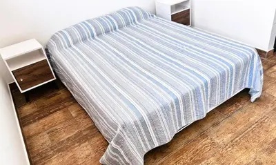 a bed with a striped comforter in a room at Beach house in Punta Hermosa, central beach area in Punta Hermosa