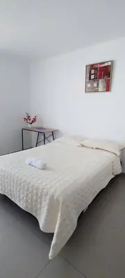 a white bed in a white room with a picture on the wall at Hotel Inkayacu Paracas Café in Paracas