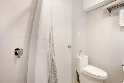 a white bathroom with a toilet and a shower at Bajada Balta Suites Spacious 3BR in Miraflores Walkable Area in Lima
