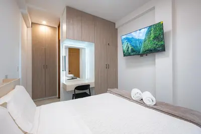 a bedroom with a white bed and a tv on the wall at Sol de Paracas Beach Homes by Vibrant in Pisco