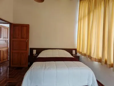 a bedroom with a bed and a window with yellow curtains at UMAY lodge house in Urubamba