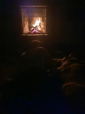 a person laying on a bed in front of a fireplace at UMAY lodge house in Urubamba