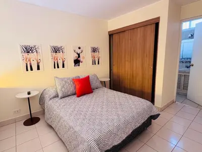 a bedroom with a bed with a red pillow at M25 Duplex a media cuadra Embajada de USA in Lima
