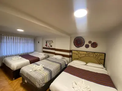 a hotel room with three beds in it at Cozy aparts & rooms in Cusco
