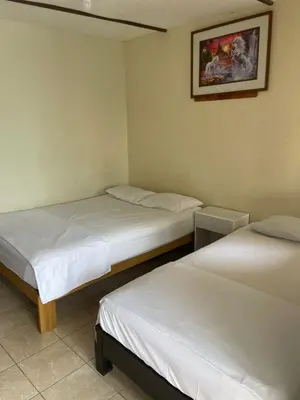 a room with two beds and a picture on the wall at HOSPEDAJE VISTA Del SOL PARACAS in Paracas