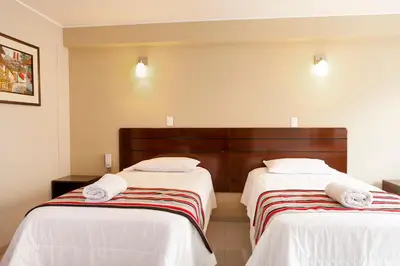 two beds in a room with white sheets and towels at Mauri in Huánuco