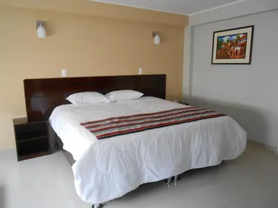 a bedroom with a large bed with white sheets and pillows at Mauri in Huánuco