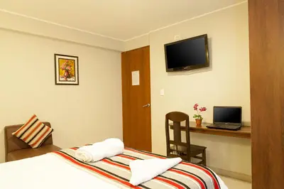 a hotel room with a bed and a desk with a laptop at Mauri in Huánuco
