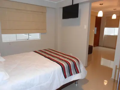 a bedroom with a bed with a striped blanket on it at Mauri in Huánuco