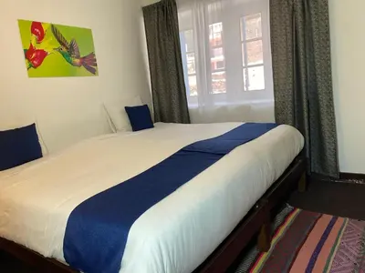 a bedroom with a large bed with blue and white sheets at Runa House2 in Cusco