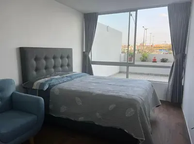 a bedroom with a bed and a chair and a window at Departamento cómodo a 20 minutos del aeropuerto in Lima