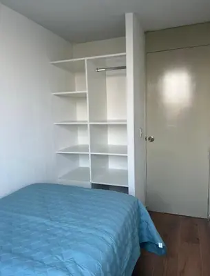 a bedroom with a blue bed and white shelves at Departamento cómodo a 20 minutos del aeropuerto in Lima