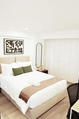 a white bedroom with a large bed and a mirror at 1BDR Modern apartment in Barranco in Lima