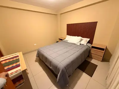 a bedroom with a bed with a wooden headboard at Tres Cruces Private Rooms in Cusco
