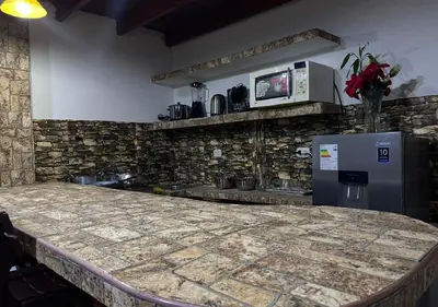 a kitchen with a stone counter top and a refrigerator at Rustic Getaway in San Bartolo in San Bartolo