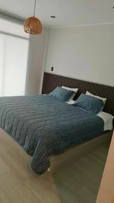 a bedroom with a bed with a blue blanket and pillows at Punta Caleta Punta Hermosa in Punta Hermosa