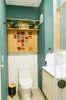 a bathroom with a toilet and a green wall at 5 stars Stylish Andean Stay - CUSCO in Cusco