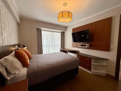 a hotel room with a bed and a flat screen tv at Departamento Graña in Lima